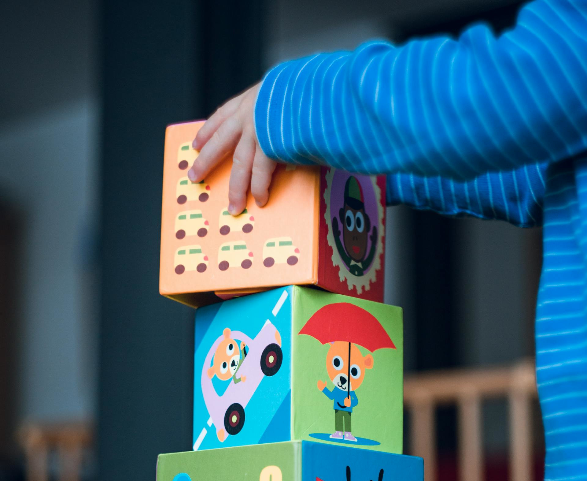 A child places play blocks on top of one another.