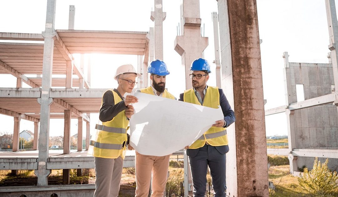 A team of architects consult over a building plan.