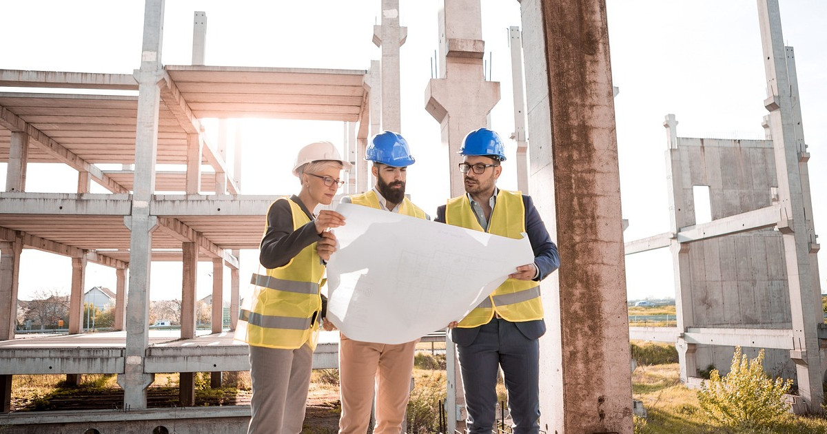 A team of architects consult over a building plan.